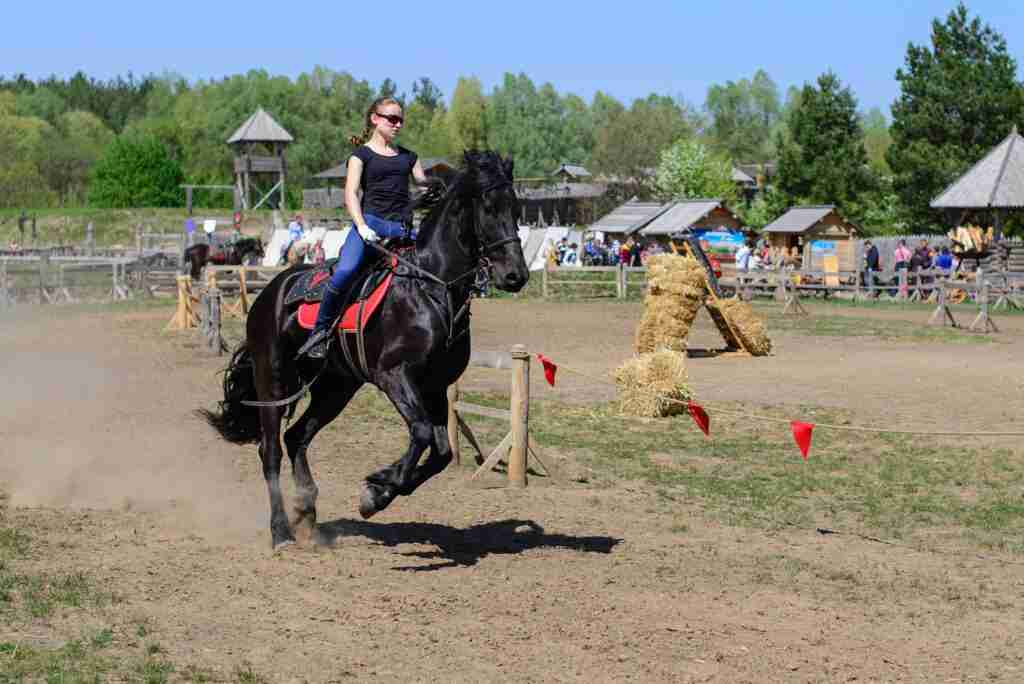 woman riding black running horse